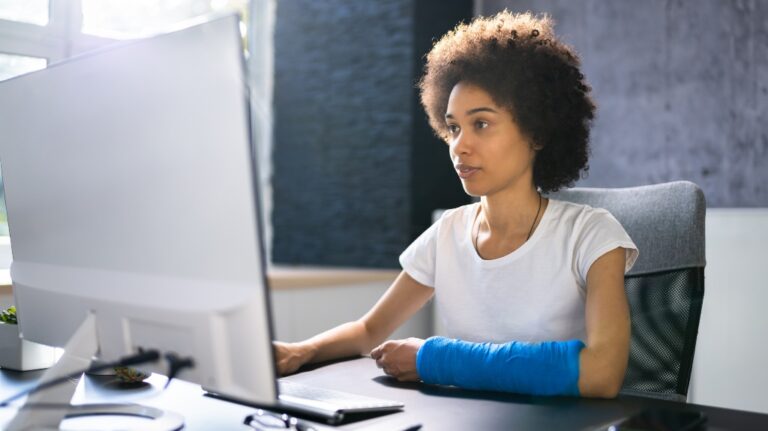 Woman with a broken arm at a computer