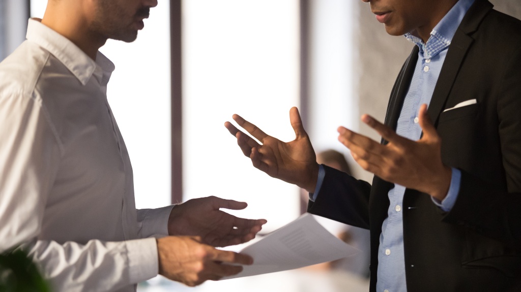 two businessmen arguing over a paper