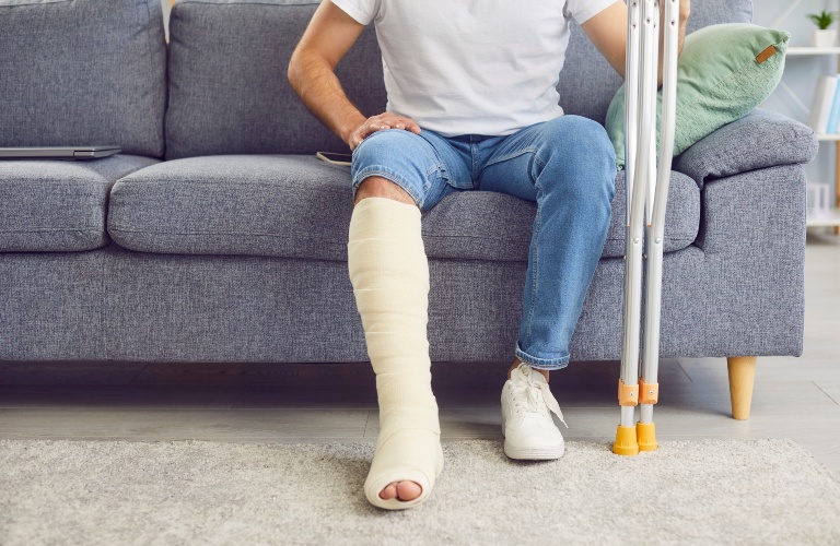 man with a broken leg sits on the sofa