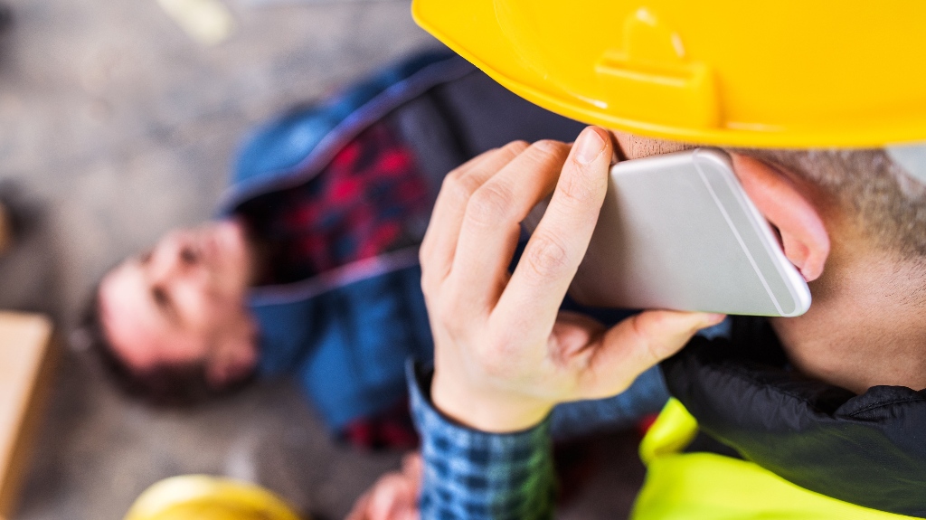 Colleague giving first aid to unconscious worker after accident
