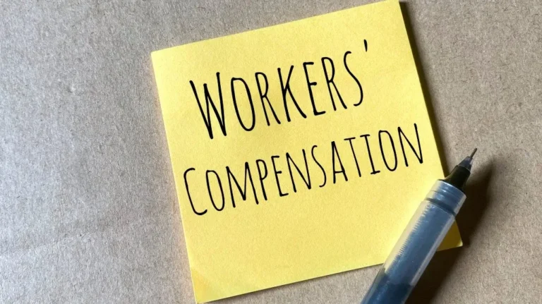 Yellow sticky note with "WORKERS' COMPENSATION" written in black ink, next to a black pen.